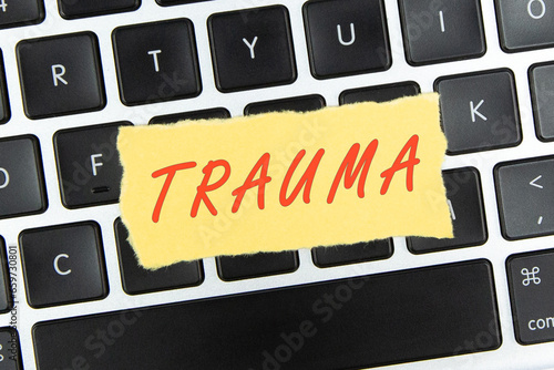 “trauma” word on torn paper on top of laptop keyboard