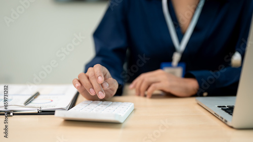Close up view of businesswoman working with calculator at her office desk.