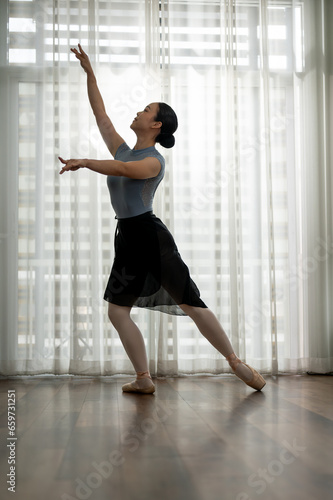 Beautiful woman performing a ballet dance, practicing her dance move at home.