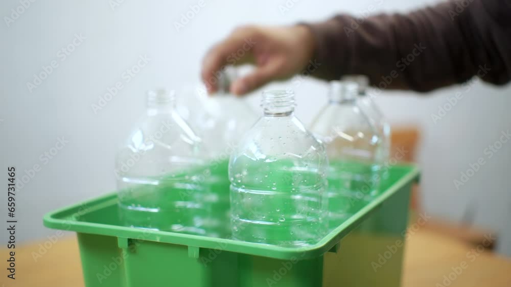 Close-up shot hand collecting and separating recycling plastic bottles putting into recycle garbage box . Sorting waste plastic bottles a trash bin at home. Close-up shot hand collecting and separating recycling plastic bottles putting into recycle garbage box . Sorting waste plastic bottles a trash bin at home.
