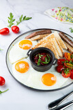 English breakfast with grilled sausages, scrambled eggs, cherry tomatoes and toast