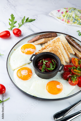 English breakfast with grilled sausages, scrambled eggs, cherry tomatoes and toast