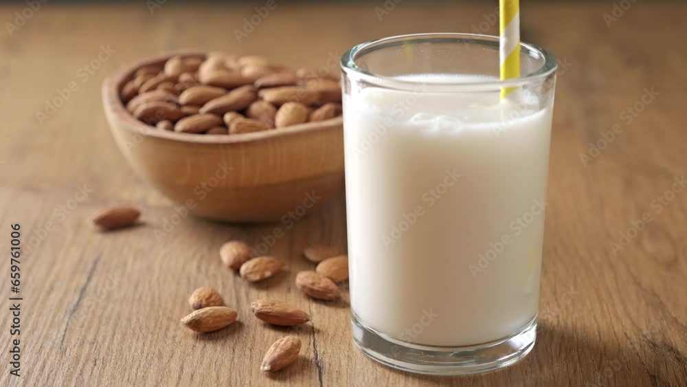 Almond milk is stirred in a glass. Vegan lactose free milk. Plant based milk and almonds. Almond milk is stirred in a glass. Vegan lactose free milk. Plant based milk and almonds.