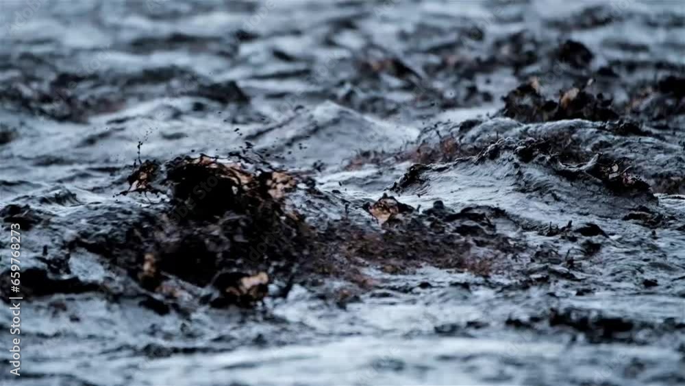 Black, muddy, turbulent water flows down a river violently after heavy rain fall Black, muddy, turbulent water flows down a river violently after heavy rain fall
