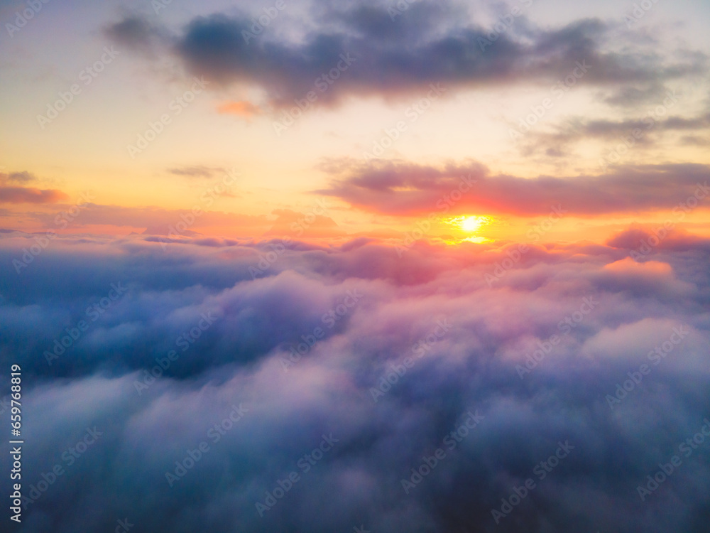 High levels of clouds and fog float in the late rainy season and early winter. The orange sun shines through the morning mist. View of mountains in the distance, mountain peaks High levels of clouds and fog float in the late rainy season and early winter. The orange sun shines through the morning mist. View of mountains in the distance, mountain peaks