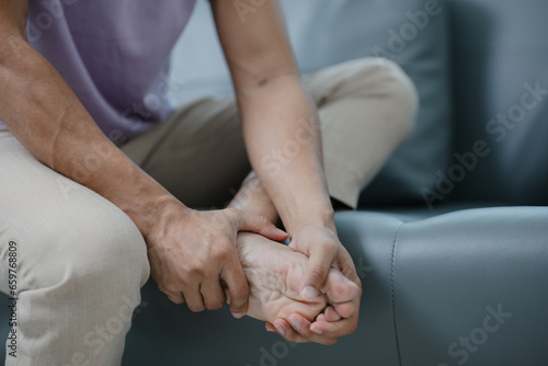 Middle-aged man has knee pain sitting on the sofa