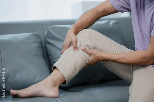 Middle-aged man has knee pain sitting on the sofa
