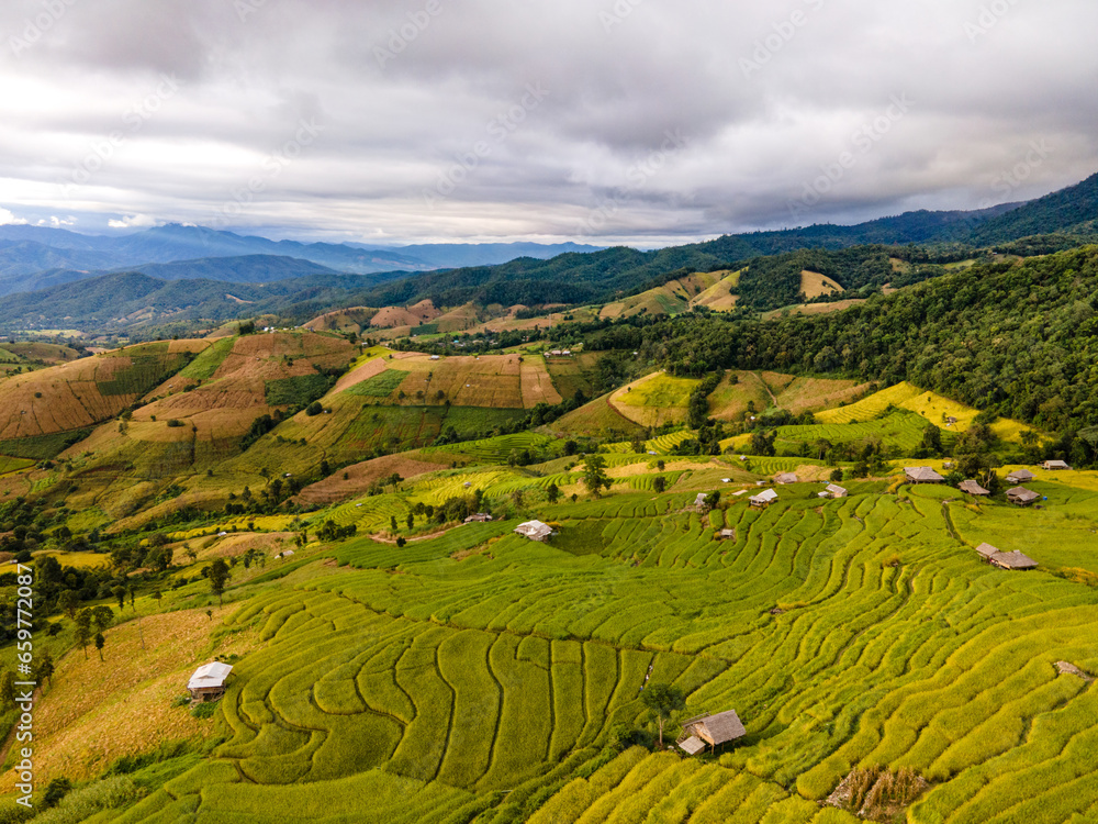 Aerial shot from drone. Green rice planting season and mysterious golden rice fields. Rice terraces. Rainy season and atmosphere after rain at Pa Bong Piang villagers, Chiang Mai, Thailand.