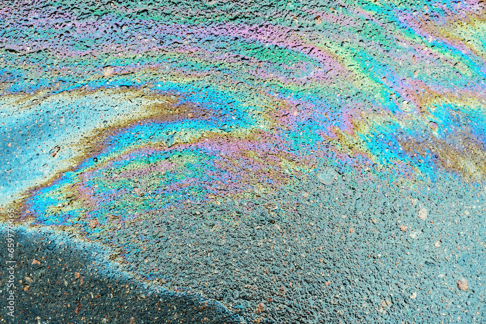 Obraz premium Leakage of oil or gasoline from under the car on the asphalt in the parking lot