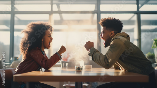 a young black couple engages in a heated argumentin a coffee shop, their faces contorted with emotion as they raise their voices in frustration.  photo