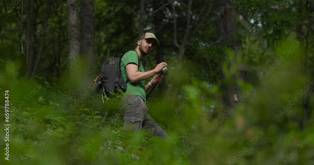 Young man in forest setting up video recording using smartphone and stick Young man in forest setting up video recording using smartphone and stick