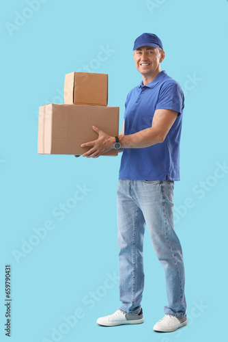 Mature courier with parcels on blue background © Pixel-Shot