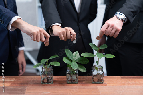 Business people put money saving into jar filled with coins and growing plant for sustainable financial planning for retirement or eco subsidy investment for environment protection. Quaint © Summit Art Creations