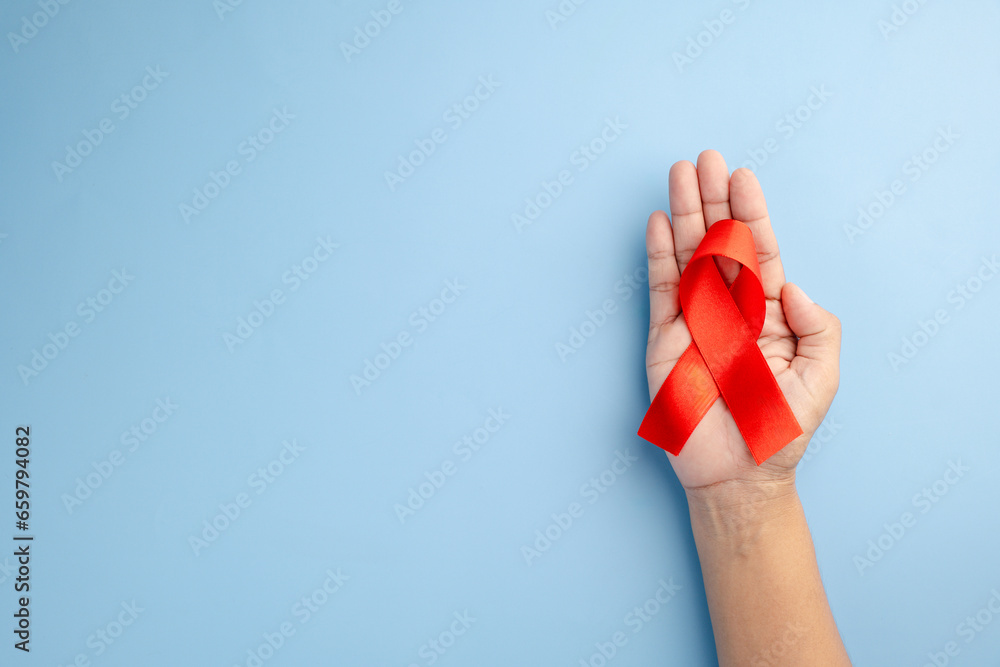 custom made wallpaper toronto digitalAIDS awareness and healthcare concept - Female hands holding a red ribbon with a stethoscope on a blue background. Promoting love, prevention, and support for a positive life.