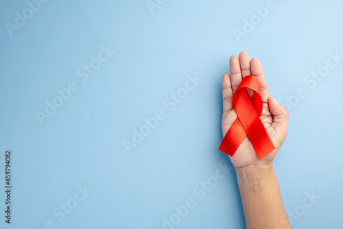 Wallpaper Mural AIDS awareness and healthcare concept - Female hands holding a red ribbon with a stethoscope on a blue background. Promoting love, prevention, and support for a positive life. Torontodigital.ca