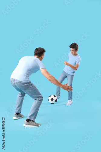 Little boy with his dad playing football on blue background