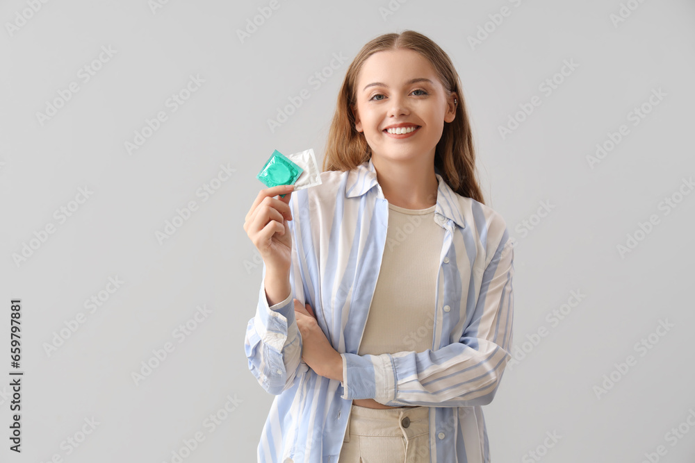 Young woman with condom on light background Young woman with condom on light background