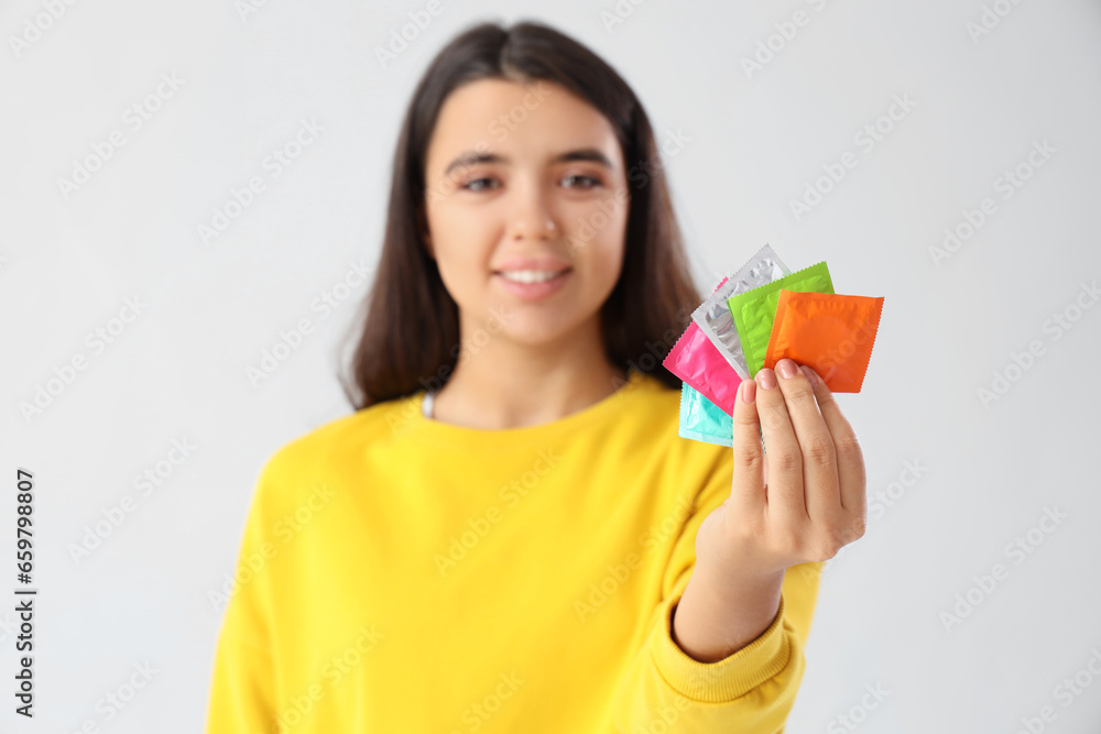 Young woman with condoms on light background. Birth control Young woman with condoms on light background. Birth control