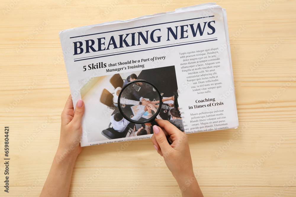 Woman with magnifying glass reading morning newspaper on wooden background Woman with magnifying glass reading morning newspaper on wooden background