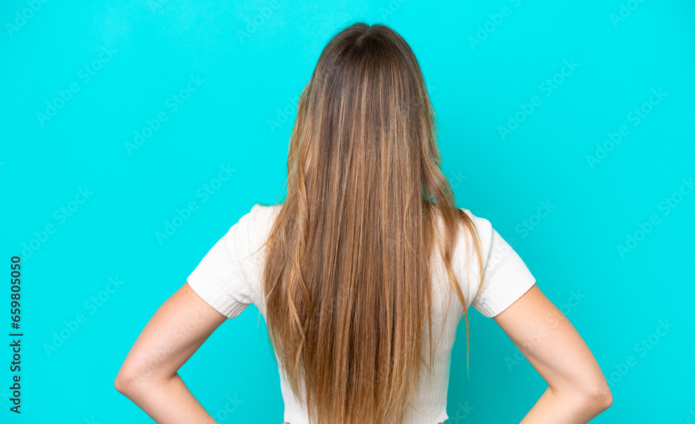 Young caucasian woman isolated on blue background in back position Young caucasian woman isolated on blue background in back position