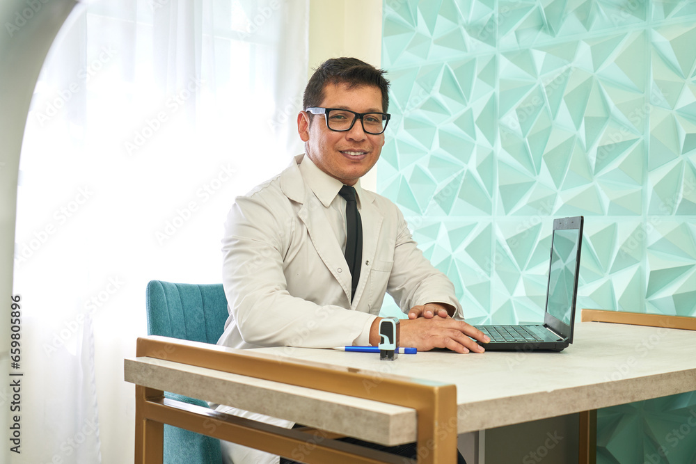 Smiling doctor sitting using laptop in an office Smiling doctor sitting using laptop in an office
