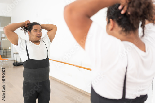confident young african american male ballet dancer preparing himself combing his hair in front of a mirror getting ready for dance preparing to perform a presentation