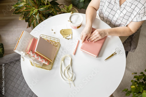 Smiling young business woman planning work making notes in paper diary at comfortable home