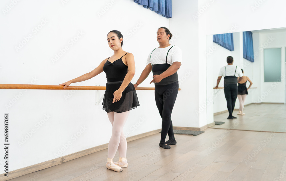 young Hispanic ballerina instructor teaching ballet to a plus sized African American adult student; concept of adult learning new skills young Hispanic ballerina instructor teaching ballet to a plus sized African American adult student; concept of adult learning new skills