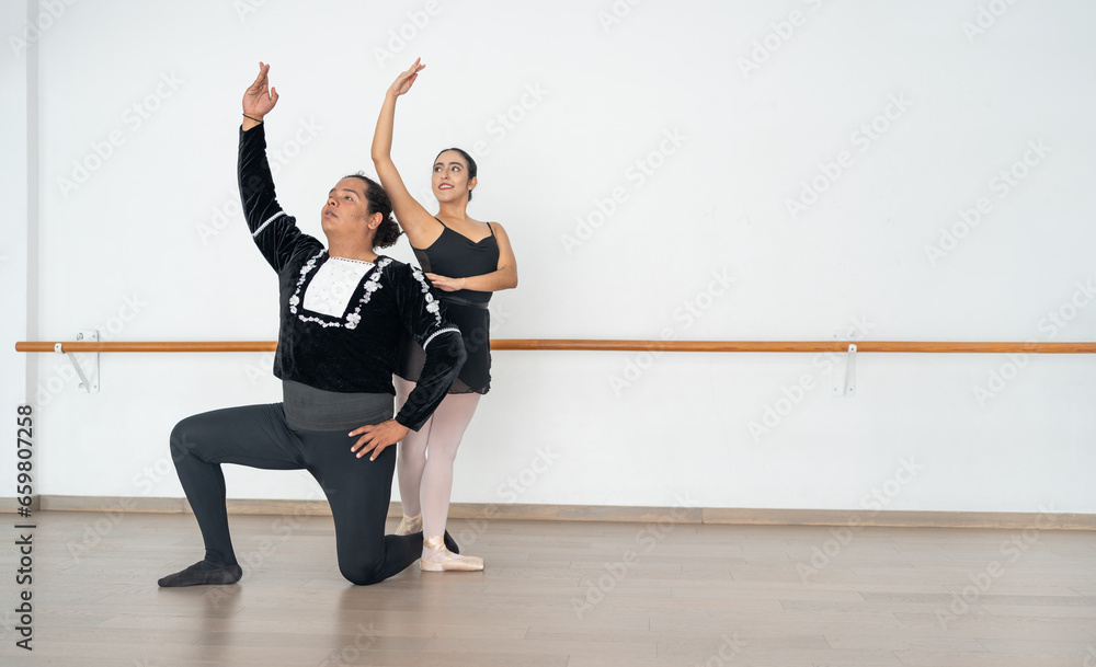 multiethnic dance partners performing an act in a dance studio in front of a big mirror; hispanic ballerina dancing with an african american plus sized young man multiethnic dance partners performing an act in a dance studio in front of a big mirror; hispanic ballerina dancing with an african american plus sized young man