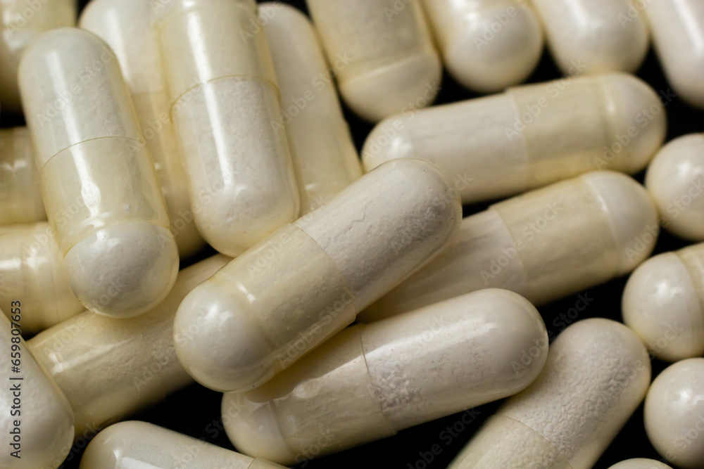 White capsules, pills on a black background. Medicine, healthcare concept. Range of pharmaceutical drugs White capsules, pills on a black background. Medicine, healthcare concept. Range of pharmaceutical drugs