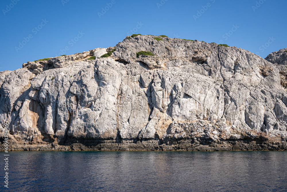 Majestic Rock Formations of Rhodes: A sea-level view of the stunning cliffs and geological wonders along the island's coastline, where the Mediterranean's blue embraces Grecian landscapes. Majestic Rock Formations of Rhodes: A sea-level view of the stunning cliffs and geological wonders along the island's coastline, where the Mediterranean's blue embraces Grecian landscapes.
