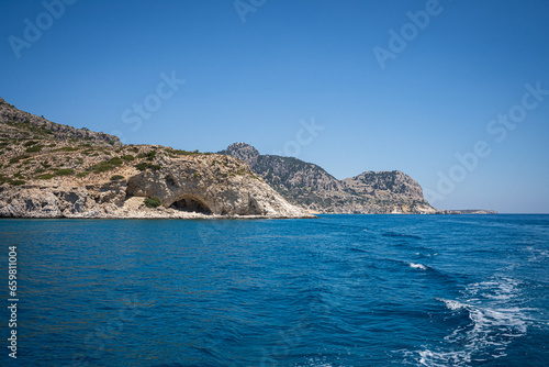 Majestic Rock Formations of Rhodes  A sea-level view of the stunning cliffs and geological wonders along the island s coastline  where the Mediterranean s blue embraces Grecian landscapes.