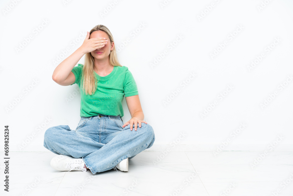 Young caucasian woman sitting on the floor isolated on white background covering eyes by hands. Do not want to see something Young caucasian woman sitting on the floor isolated on white background covering eyes by hands. Do not want to see something