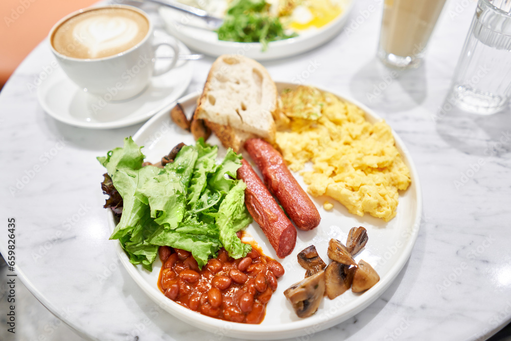 Continental breakfast. Modern Full English Breakfast with scrambled eggs, champignons, toast, beef sausages, beans, avocado and lettuce. Healthy food Served lunch in cafe