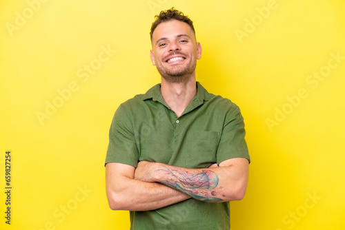 Young caucasian handsome man isolated on yellow background keeping the arms crossed in frontal position