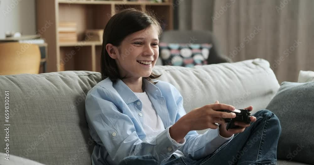 Joyful Caucasian boy, equipped with a gamepad, indulges in a video game while sitting on the couch. His happiness and gaming prowess create an atmosphere of enjoyment and skillful gaming. Joyful Caucasian boy, equipped with a gamepad, indulges in a video game while sitting on the couch. His happiness and gaming prowess create an atmosphere of enjoyment and skillful gaming.