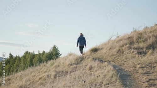 Hand-held tracking shot of an alone female hiker hiking through the Benmore Peninsula trail photo