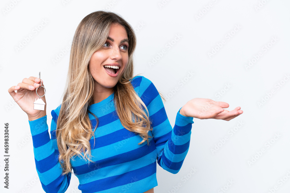 Young pretty Uruguayan woman holding home keys isolated on white background with surprise facial expression Young pretty Uruguayan woman holding home keys isolated on white background with surprise facial expression