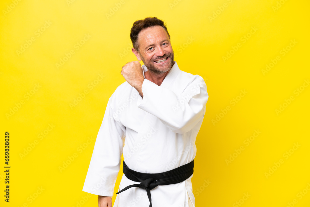 Middle age caucasian man doing karate isolated on yellow background celebrating a victory Middle age caucasian man doing karate isolated on yellow background celebrating a victory