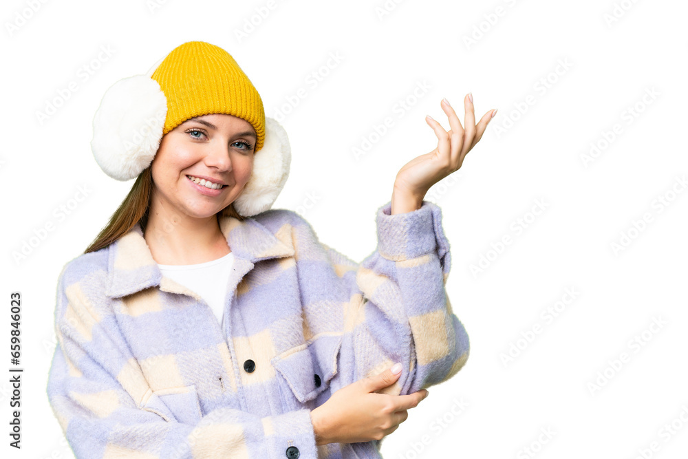 Young blonde woman wearing winter muffs over isolated chroma key background extending hands to the side for inviting to come