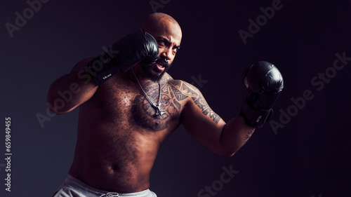 Mixed-race man threw a punch in the air with boxing gloves in a studio shot © EvaHM