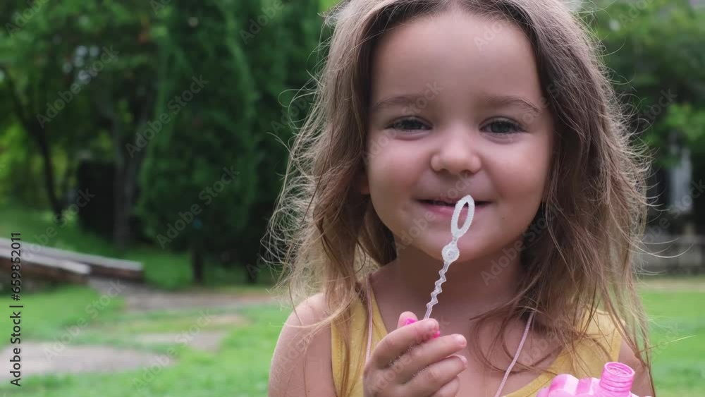 Portrait of the child with soap bubbles outdoors