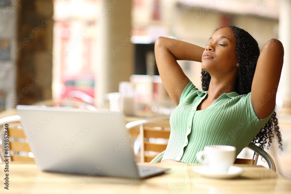 Black woman with laptop resting in a restaurant