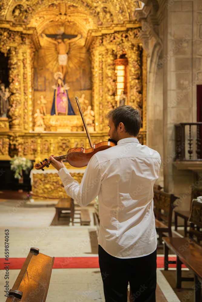Person playing violin. Caucasian violinist man wearing classical clothes and performing in a closed space, church. Live performance. Vertical image