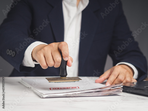 Картината върху платно Businessman in a suit stamped for rejected documents while sitting at the table