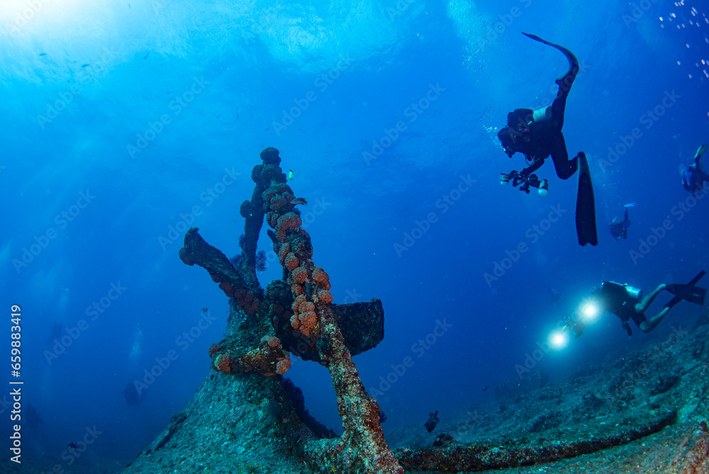 Scuba divers explores propeller of sunken shipwreck Scuba divers explores propeller of sunken shipwreck