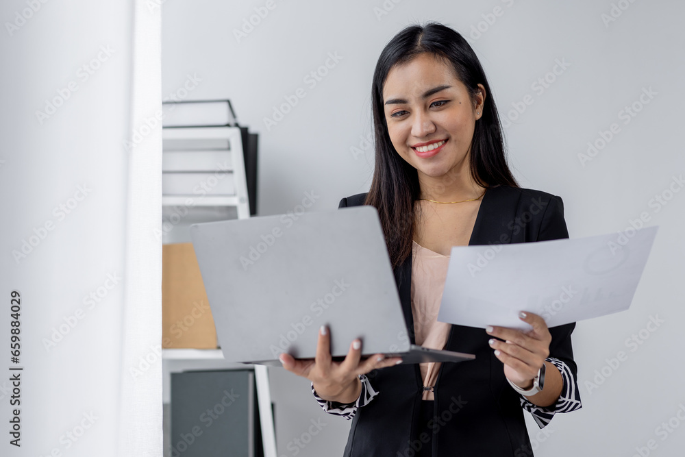 Portrait of young asian woman, company worker in documents smiling and holding digital Laptop, standing over office background Portrait of young asian woman, company worker in documents smiling and holding digital Laptop, standing over office background