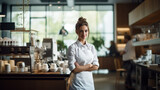 Barista looking at the camera in a stylish coffee shop. Portrait of smiling young woman in coffee shop. Person at work, small business concept.