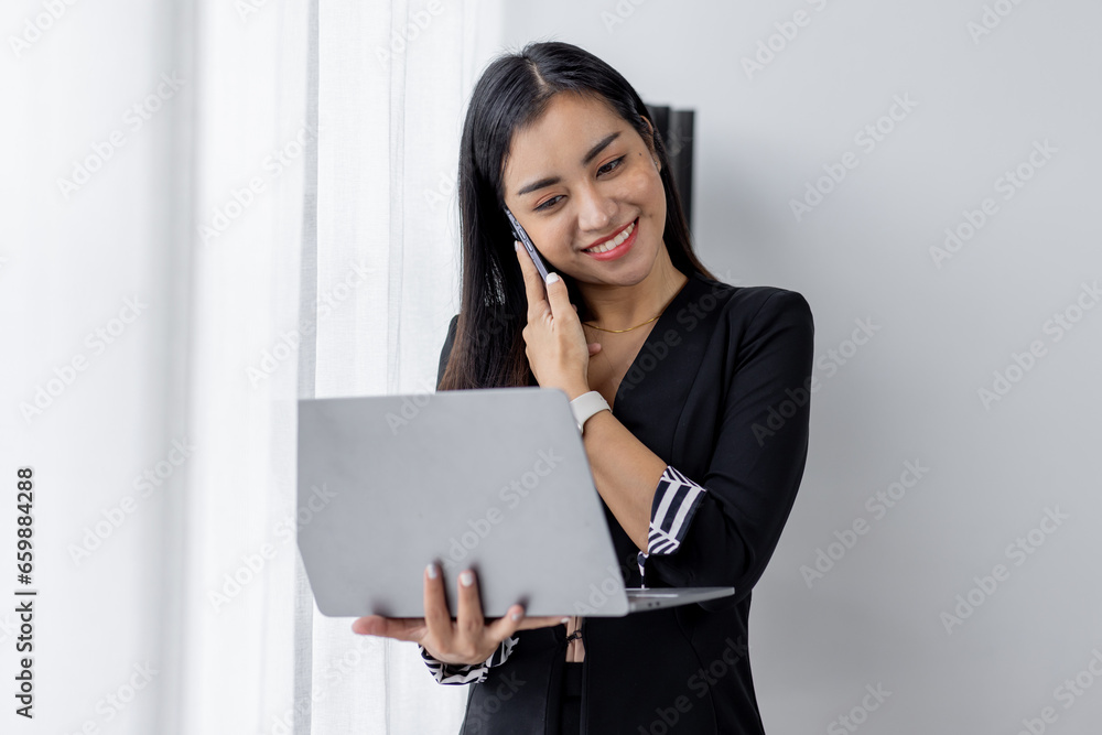 Portrait of young asian woman, company worker in documents smiling and holding digital Laptop, standing over office background