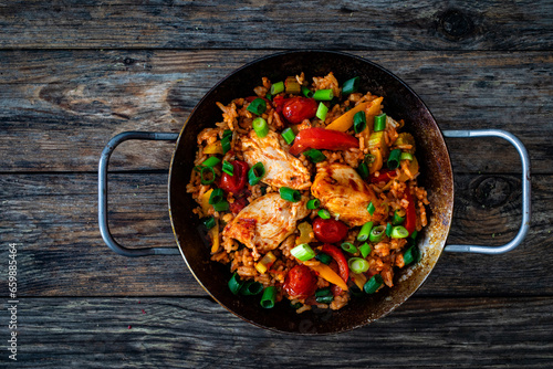 Jambalaya one pot dish - fried chicken breasts with white rice, tomatoes, bell pepper and celery on wooden table
 photo